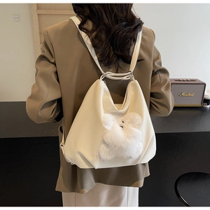 Detail showing versatile cream tote bag with cute plush bunny decor worn as a backpack