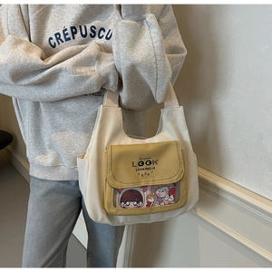 Detail of canvas tote bag with yellow front pocket and transparent character window