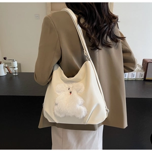Detail showing plush rabbit patch on cream tote bag in a cozy cafe setting