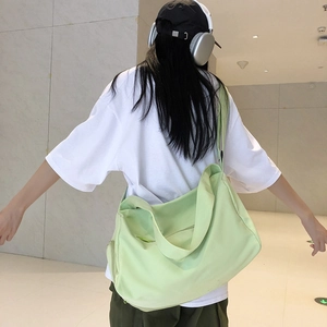 Rear view of a model carrying the large light green canvas sports bag in a minimalist hall