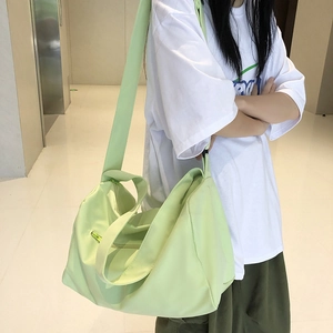 Close-up of light green nylon yoga bag with wide shoulder strap and zipper pocket
