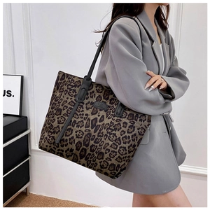 Leopard print tote bag with black leather straps shown as a stylish shoulder bag