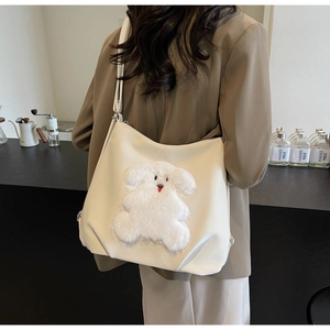 Detailed view of white PU tote bag with cute plush animal patch on a model outfit