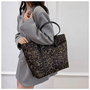 Detailed view of leopard print tote bag with black handles on a grey blazer model