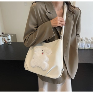 Detail of white PU leather tote featuring a plush puppy patch with shoulder strap
