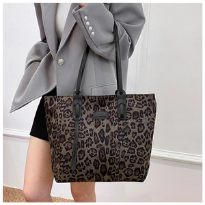 Close-up of leopard print tote bag featuring a brand logo plate and slim black shoulder straps