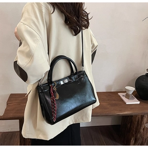 Détail d'un sac à main noir en similicuir avec fermoir rotatif argenté et décor tissé