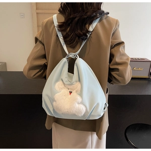 Light blue backpack featuring a white plush animal patch shown on model's back