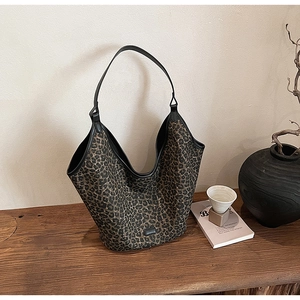 Detail of trendy leopard print hobo tote bag with black straps on a wooden table