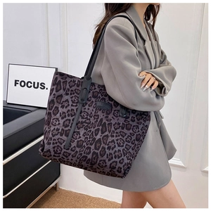 Detail of leopard print tote bag with black leather shoulder straps on model