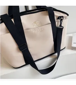 Detail of adjustable black shoulder strap and gold embroidery on beige nylon tote bag