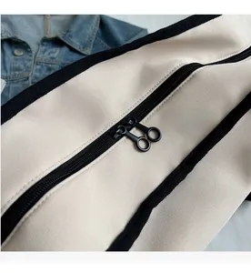 Detail view of smooth metal ring double zipper on a cream canvas fitness bag