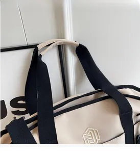 Close-up of durable canvas handles with padded grip and logo detail on travel bag