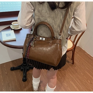 Sac à main vintage marron avec fermoir argenté et foulard en soie sur une table