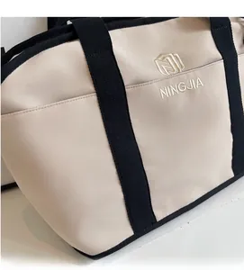 Close-up of beige fitness bag featuring black straps and NINGJIA embroidered logo detail