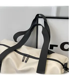 Detail of cream travel bag featuring black woven handles and durable double zippers