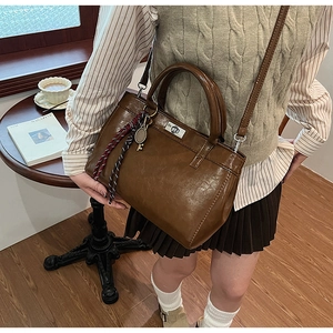 Vue détaillée d'un sac vintage marron brillant avec une breloque en cordon tressé coloré