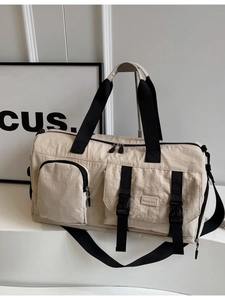 Sac de voyage beige en nylon avec sangles noires sur une plateforme blanche épurée