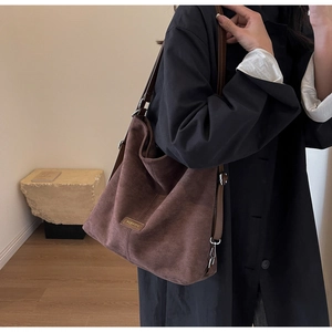 Detail of a brown faux suede tote bag with FASHION label on a stylish dark coat