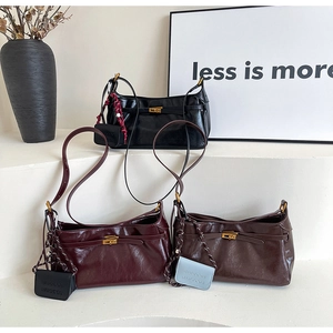 Three colors of retro glossy leather shoulder bags with gold hardware on white pedestals