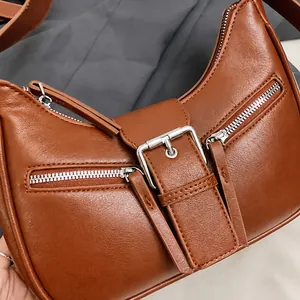 Detail view of smooth caramel leather texture with silver buckles and dual zip closures