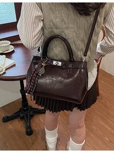 Sac bandoulière marron rétro avec breloque raquette et fermoir argenté dans un café