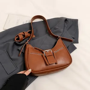 Detail show of caramel leather shoulder bag with silver buckles and dual straps