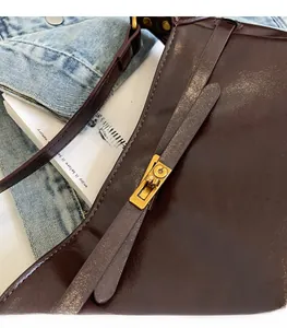 Detail of vintage caramel leather shoulder bag featuring a gold buckle and wax finish texture