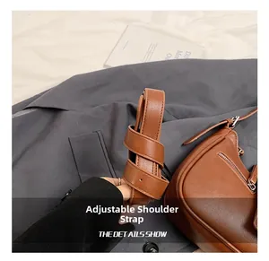 Detail view of the adjustable brown leather strap with metallic buckle on a handbag