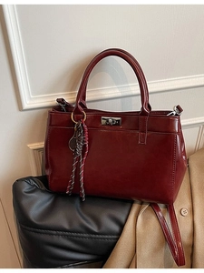 Sac à main élégant en cuir bordeaux avec fermoir argenté et breloque tissée en studio