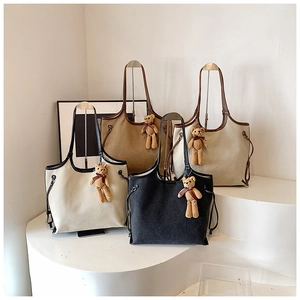 Detail of four canvas tote bags in cream and khaki with leather handles and bear charms
