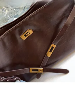 Detail of vintage brown oil wax leather bag with golden metal C-clasp and texture