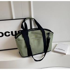 Detail of light green fitness bag with embroidered logo and detachable black shoulder strap