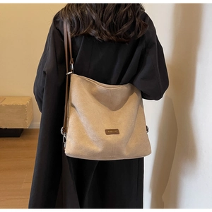 Detail of minimalist beige PU leather shoulder bag with dark brown fashion logo label