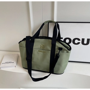 Detail of light green yoga tote with embroidered gold logo and adjustable black strap