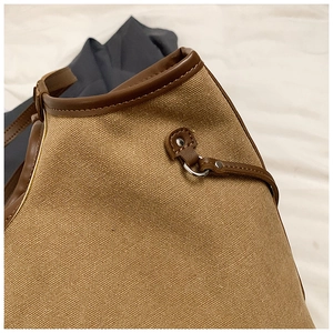 Close-up of canvas tote bag stitching with premium leather trim and silver metal hardware