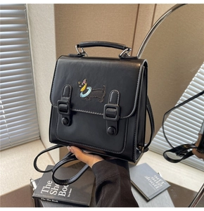 Détail d'un sac à dos noir en similicuir avec broderie de chien et bretelles rétro chic