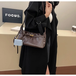 Detail view of a vintage dark brown leather shoulder bag with a gold metal clasp