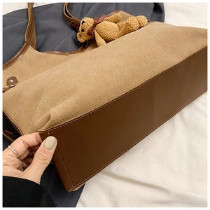 Detail of khaki canvas tote bag with brown leather base and cute bear keychain