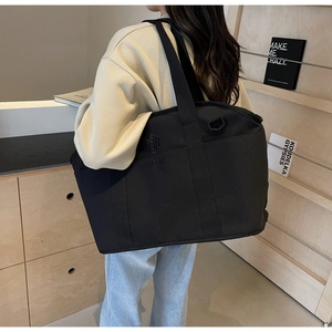 Detail of black canvas yoga bag featuring reinforced handles and side storage pockets