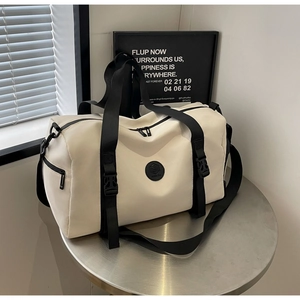 Close-up of cream travel bag showing reinforced buckle and adjustable shoulder strap