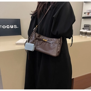 Detail of vintage dark brown leather underarm bag with light blue mini pouch on a strap