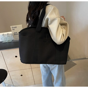 Detail of NINGJIA black canvas tote showing the embroidered logo and spacious interior structure