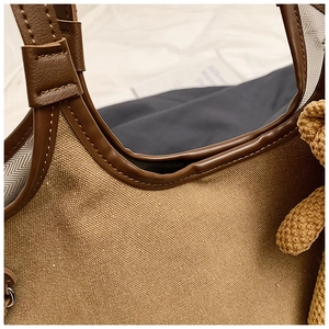 Close-up of canvas tote bag with leather trim, herringbone lining and cute bear charm