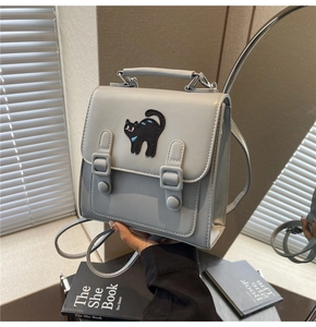 Détail d'un sac à dos gris clair en cuir PU avec patch brodé chat noir et boucle décorative