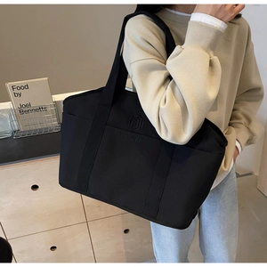 Close-up of black NINGJIA tote bag showing durable fabric and embossed logo detail
