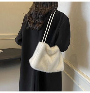 Close-up of white plush shoulder bag with soft faux fur texture on a model side view