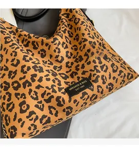 Close-up of leopard print tote bag with logo patch, golden chain, and faux fur texture