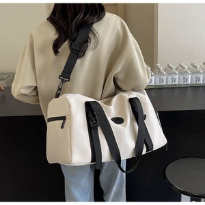 Detail of a beige travel bag with black nylon straps and waterproof fabric on a model
