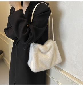 Close-up of white plush shoulder bag on a black coat, winter fashion furry handbag detail